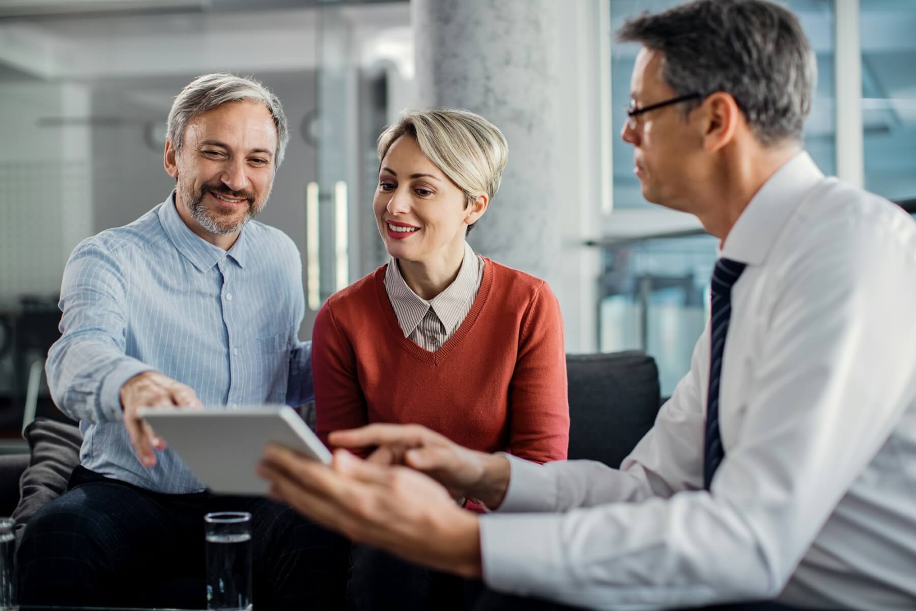 happy mid adult couple using touchpad with their financial consultant in the office 1.jpg