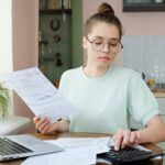 young beautiful woman budgeting managing utilities expenses writing financial plan.jpg